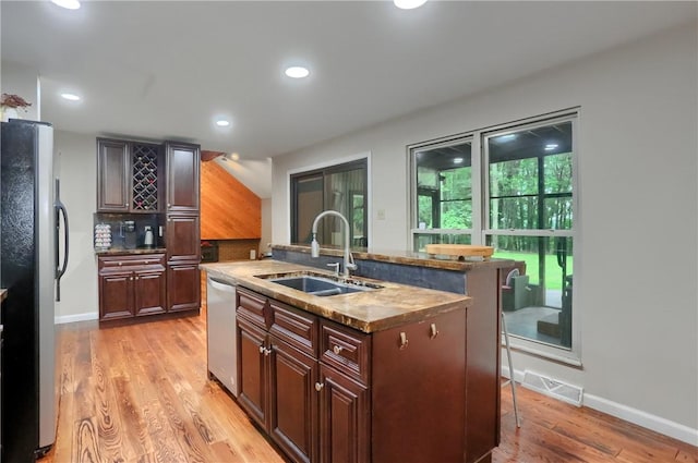 1259 Lakevue Dr, Penn Twp, PA 16001 - kitchen with appliances with stainless steel finishes, light wood-type flooring, a center island with sink, a breakfast bar, and decorative backsplash