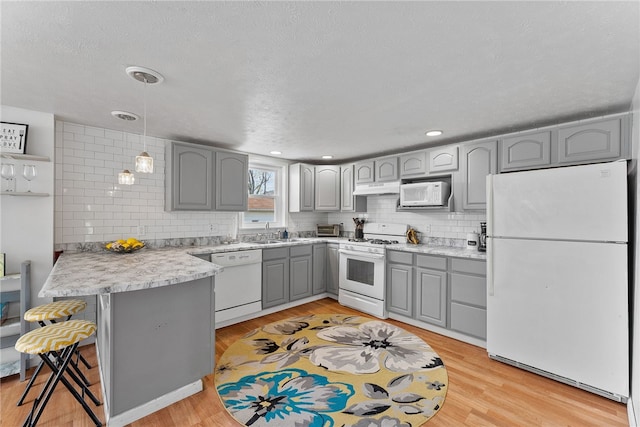 205 Cottage St, Neville Twp, PA 15225 - kitchen with white appliances, gray cabinetry, a peninsula, under cabinet range hood, and tasteful backsplash