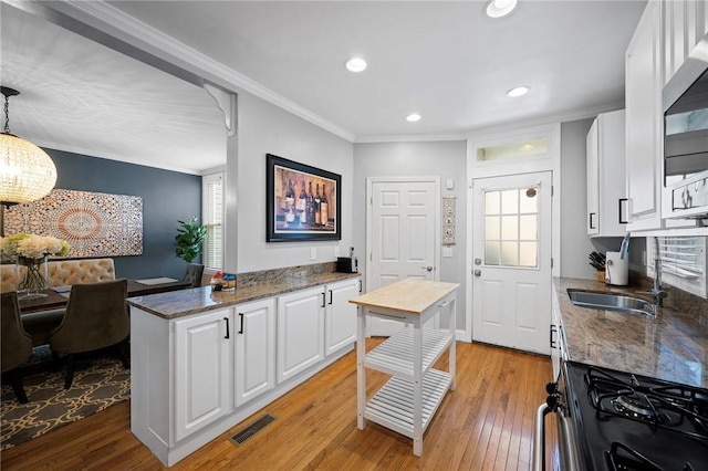 215 Emerson St, Shadyside, PA 15206 - kitchen with black gas range, white cabinetry, healthy amount of natural light, ornamental molding, and recessed lighting