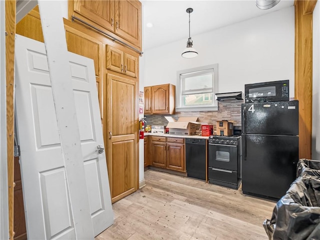 1556 Island Ave, Stowe Twp, PA 15136 - kitchen featuring black appliances, wall chimney range hood, light wood-type flooring, brown cabinetry, and tasteful backsplash