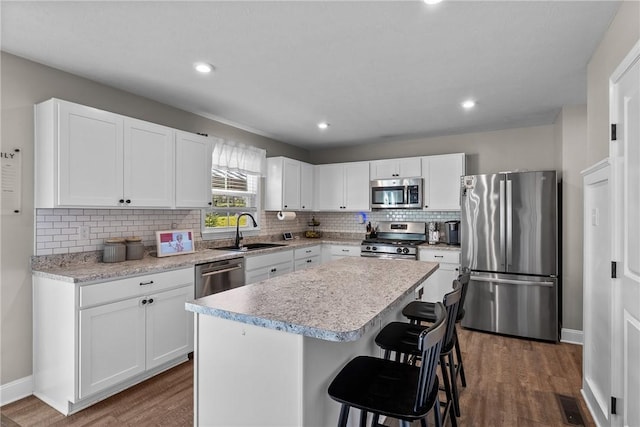 226 Stevens Ct, South Strabane, PA 15301 - kitchen with stainless steel appliances, dark wood-style floors, tasteful backsplash, a kitchen bar, and a center island