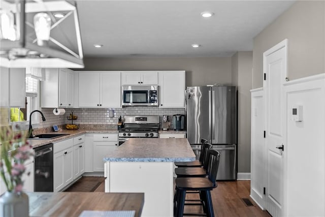 226 Stevens Ct, South Strabane, PA 15301 - kitchen with appliances with stainless steel finishes, decorative backsplash, white cabinets, a kitchen island, and a breakfast bar