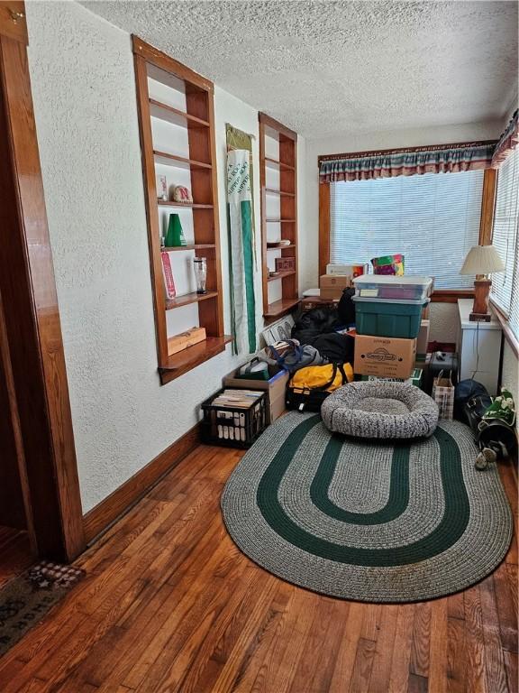418 S Main St, Slippery Rock Boro, PA 16057 - living area featuring a textured wall, a textured ceiling, built in shelves, and hardwood / wood-style floors