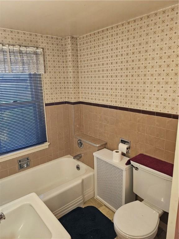 418 S Main St, Slippery Rock Boro, PA 16057 - bathroom featuring a bathtub, tile walls, wainscoting, and wallpapered walls
