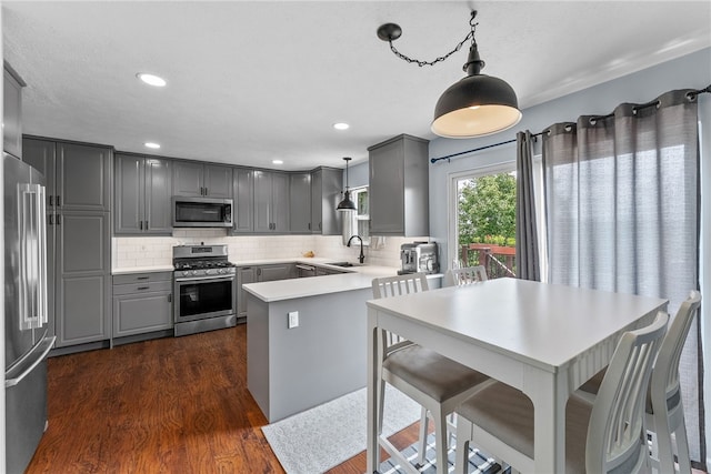 1020 Granite Dr, South Fayette, PA 15057 - kitchen with stainless steel appliances, gray cabinets, a peninsula, dark wood-type flooring, and decorative backsplash