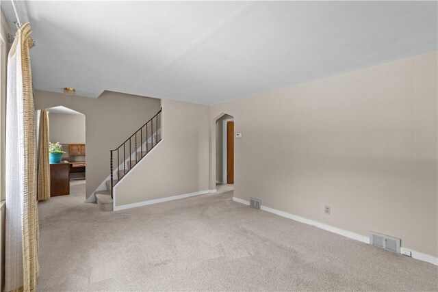1031 Stratmore St, Ingram, PA 15205 - unfurnished living room featuring arched walkways, carpet, and stairway
