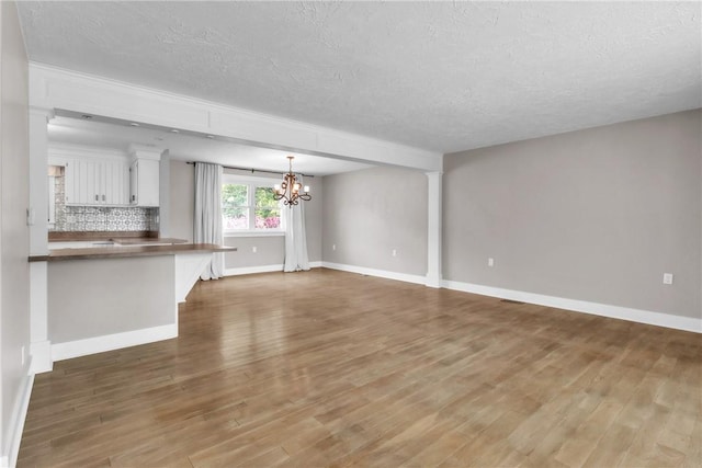 626 Solomon Temple Rd, Unity Twp, PA 15650 - unfurnished living room with a textured ceiling, a chandelier, and wood finished floors