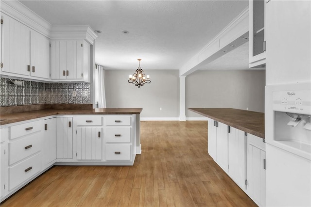 626 Solomon Temple Rd, Unity Twp, PA 15650 - kitchen with decorative backsplash, white cabinetry, a chandelier, a peninsula, and butcher block counters