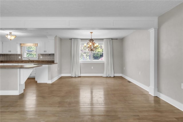 626 Solomon Temple Rd, Unity Twp, PA 15650 - kitchen featuring white cabinets, a chandelier, dark countertops, decorative backsplash, and wood finished floors