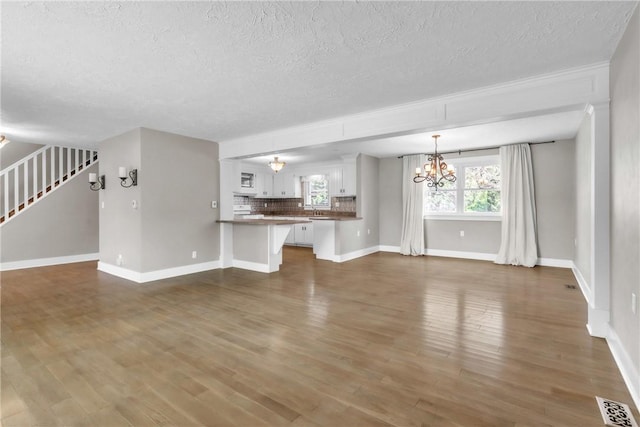 626 Solomon Temple Rd, Unity Twp, PA 15650 - unfurnished living room with a chandelier, a textured ceiling, dark wood-style flooring, and stairway