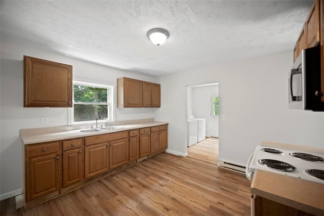 1153 Robinson Hwy, Robinson Twp Wsh, PA 15057 - kitchen with stainless steel microwave, washer and dryer, light wood-type flooring, brown cabinets, and a textured ceiling