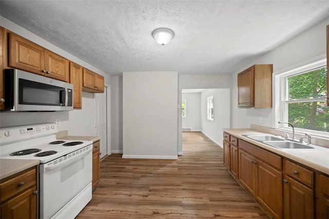 1153 Robinson Hwy, Robinson Twp Wsh, PA 15057 - kitchen with stainless steel microwave, white electric range, light countertops, light wood-style floors, and brown cabinetry