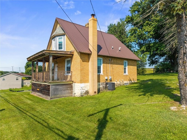 943 State Route 66, Gilpin Twp, PA 15690 - rear view of property featuring a chimney, a lawn, brick siding, covered porch, and a metal roof