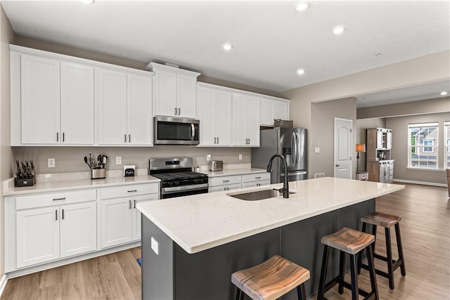 136 Sweetwater Dr, Moon/Crescent Twp, PA 15108 - kitchen with stainless steel appliances, white cabinetry, a kitchen island with sink, light wood-style flooring, and a kitchen breakfast bar