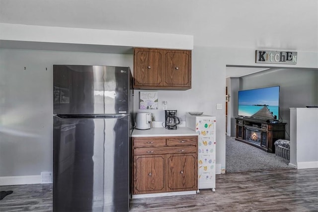 360 Jo Ann Dr, Monessen, PA 15062 - kitchen with freestanding refrigerator, dark wood-type flooring, a lit fireplace, and brown cabinets