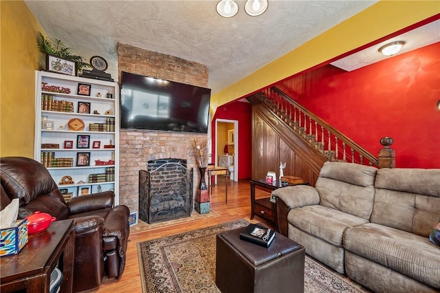 322 Darsie St, Bloomfield, PA 15224 - living area featuring wood finished floors, stairs, a brick fireplace, and a textured ceiling