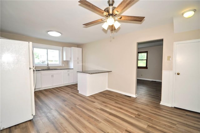 312 Delmont Ave, Coolbaugh Twp, PA 15012 - kitchen with freestanding refrigerator, white cabinetry, a peninsula, light wood-type flooring, and ceiling fan