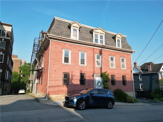 117 S Mckean St, City Of But Ne, PA 16001 - view of front facade featuring mansard roof, brick siding, and roof with shingles