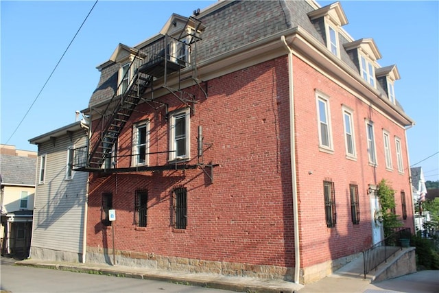 117 S Mckean St, City Of But Ne, PA 16001 - view of side of property featuring mansard roof, a balcony, brick siding, and a shingled roof