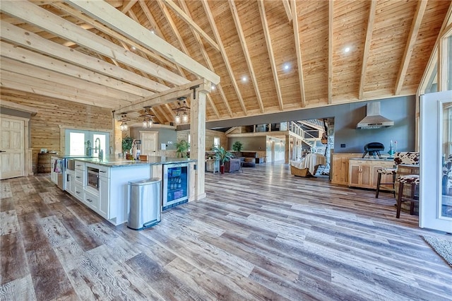 1060 Wattersonville Rd, Coolbaugh Twp, PA 16218 - kitchen featuring beverage cooler, wall chimney range hood, open floor plan, a wood ceiling with exposed beams, and white cabinetry