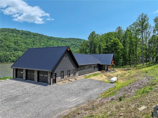 1060 Wattersonville Rd, Coolbaugh Twp, PA 16218 - view of front of home with a wooded view, stone siding, a metal roof, and a detached garage
