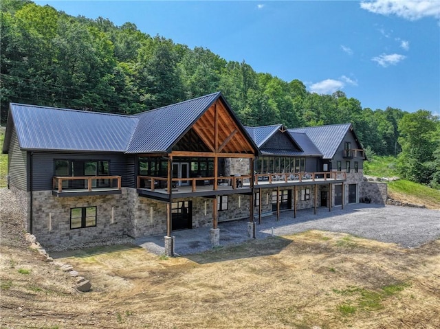 1060 Wattersonville Rd, Coolbaugh Twp, PA 16218 - rear view of property featuring stone siding, a forest view, and a metal roof
