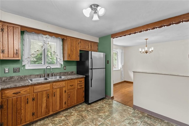 433 Wyndhurst Dr, Moon/Crescent Twp, PA 15108 - kitchen featuring freestanding refrigerator, brown cabinetry, a chandelier, hanging light fixtures, and dark countertops