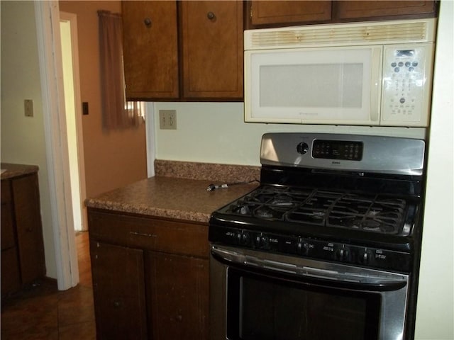 243 Byron Rd, Ross Twp, PA 15237 - kitchen featuring stainless steel gas range, white microwave, dark tile patterned floors, and dark countertops