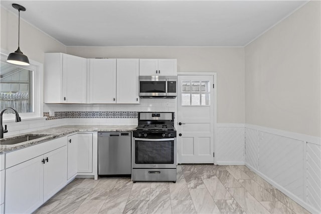 4506 Bowes Ave, West Mifflin, PA 15122 - kitchen featuring appliances with stainless steel finishes, white cabinetry, light stone countertops, healthy amount of natural light, and a wainscoted wall