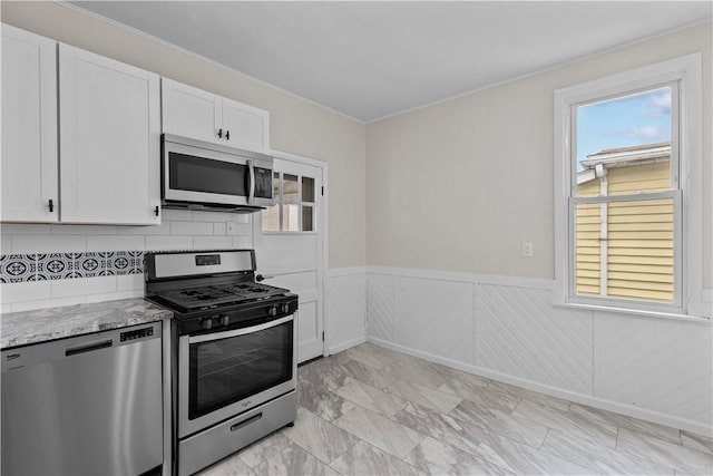 4506 Bowes Ave, West Mifflin, PA 15122 - kitchen with stainless steel appliances, a wainscoted wall, light stone counters, white cabinets, and light marble finish floors