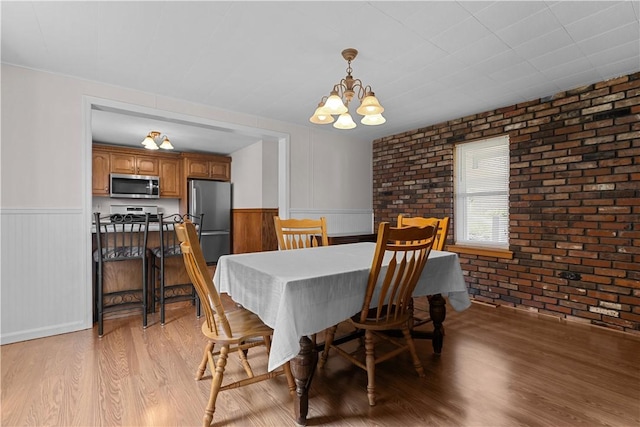 217 Orchard St, West Deer, PA 15006 - dining area featuring light wood-style flooring, a chandelier, wainscoting, and brick wall