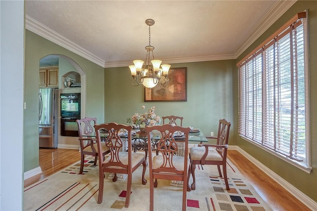 2023 Sterling Dr, South Fayette, PA 15057 - dining area featuring light wood-style floors, healthy amount of natural light, arched walkways, a chandelier, and ornamental molding