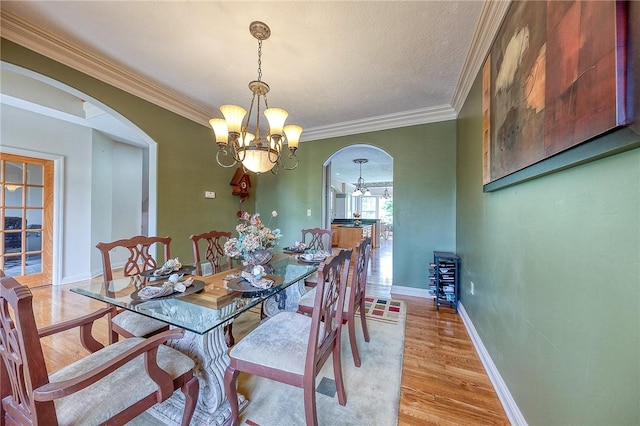 2023 Sterling Dr, South Fayette, PA 15057 - dining area featuring arched walkways, a chandelier, light wood-style floors, and ornamental molding