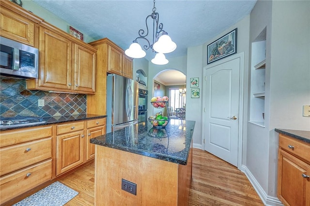 2023 Sterling Dr, South Fayette, PA 15057 - kitchen featuring stainless steel appliances, arched walkways, light wood finished floors, decorative backsplash, and a kitchen island