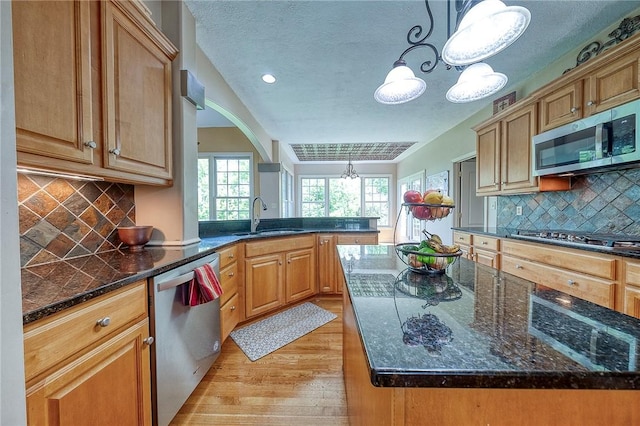 2023 Sterling Dr, South Fayette, PA 15057 - kitchen with appliances with stainless steel finishes, light wood-style floors, a peninsula, a chandelier, and dark stone counters