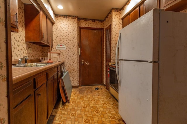 502 3rd St, Pitcairn, PA 15140 - kitchen featuring freestanding refrigerator, wallpapered walls, stove, light floors, and brown cabinetry