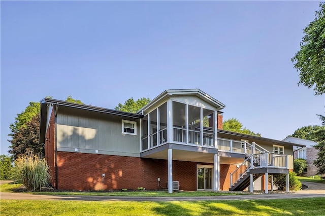 425 Ridge Rd, Hempfield Twp Wml, PA 15601 - back of property with brick siding, a sunroom, stairway, a deck, and a lawn