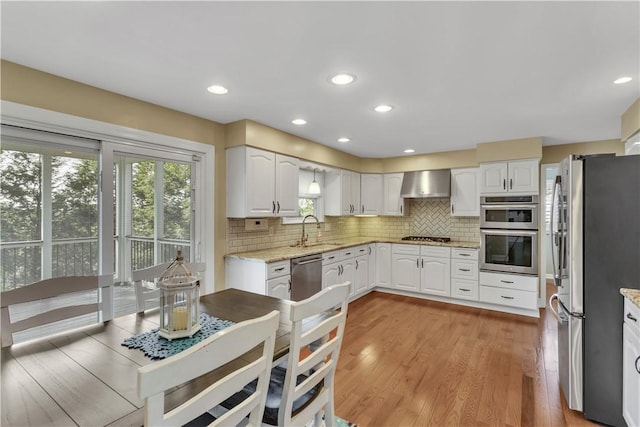 425 Ridge Rd, Hempfield Twp Wml, PA 15601 - kitchen featuring appliances with stainless steel finishes, wall chimney range hood, tasteful backsplash, light stone counters, and white cabinets