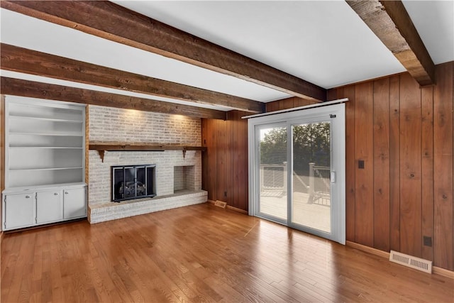425 Ridge Rd, Hempfield Twp Wml, PA 15601 - unfurnished living room with beam ceiling, a fireplace, wood finished floors, and wooden walls