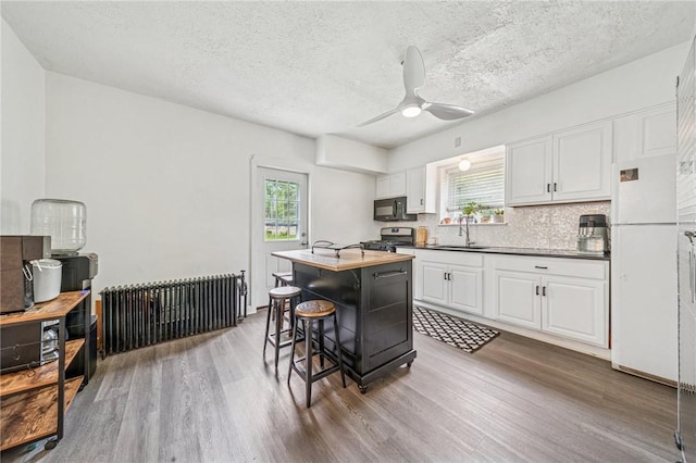 215-217 Fairlawn Dr, Monroeville, PA 15146 - kitchen with freestanding refrigerator, black microwave, stainless steel gas stove, wood finished floors, and healthy amount of natural light
