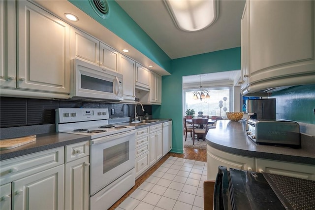 320 Fort Duquesne Blvd Unit 26N, Downtown Pgh, PA 15222 - kitchen featuring white appliances, dark countertops, decorative backsplash, a chandelier, and white cabinetry
