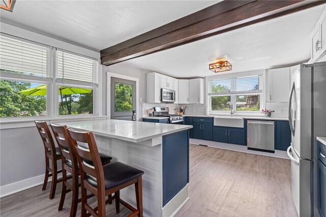 401 Stanford Ave, Ross Twp, PA 15229 - kitchen featuring appliances with stainless steel finishes, blue cabinetry, healthy amount of natural light, decorative backsplash, and beamed ceiling