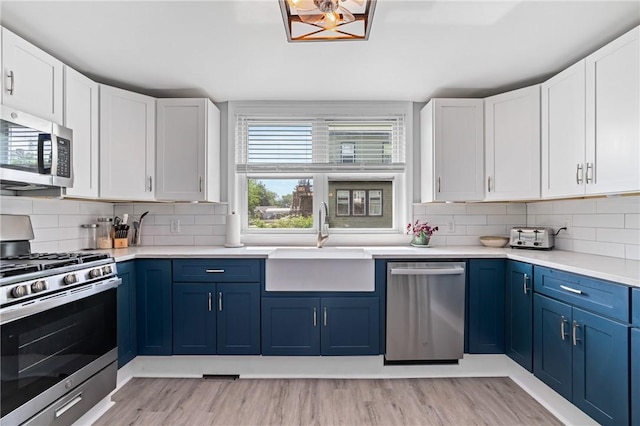 401 Stanford Ave, Ross Twp, PA 15229 - kitchen with stainless steel appliances, blue cabinetry, decorative backsplash, and light countertops