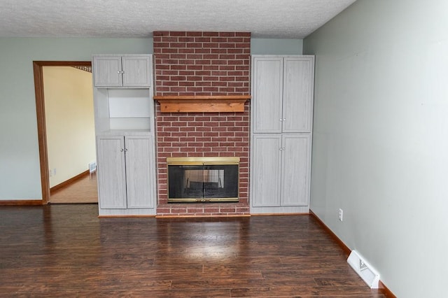 408 Victor Dr, South Union Twp, PA 15401 - unfurnished living room with dark wood-style floors, a brick fireplace, and a textured ceiling