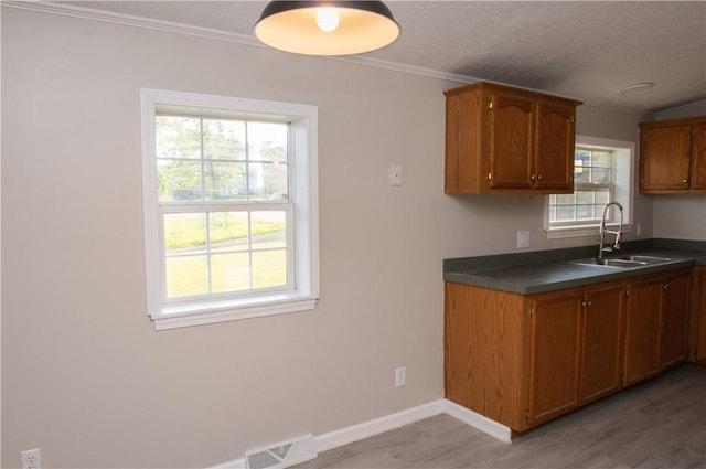 824 Emerson Ave, Farrell, PA 16121 - kitchen with dark countertops, light wood-style floors, ornamental molding, brown cabinets, and a textured ceiling