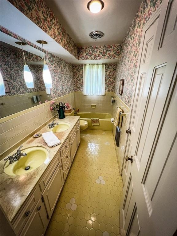 123 W Muntz Ave, Twp Of But Se, PA 16001 - bathroom featuring wallpapered walls, a wainscoted wall, double vanity, a bath, and tile walls
