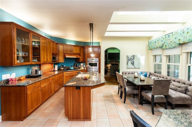 99 Wiggins Ln, South Union Twp, PA 15401 - kitchen featuring under cabinet range hood, open floor plan, arched walkways, dark stone countertops, and stainless steel appliances