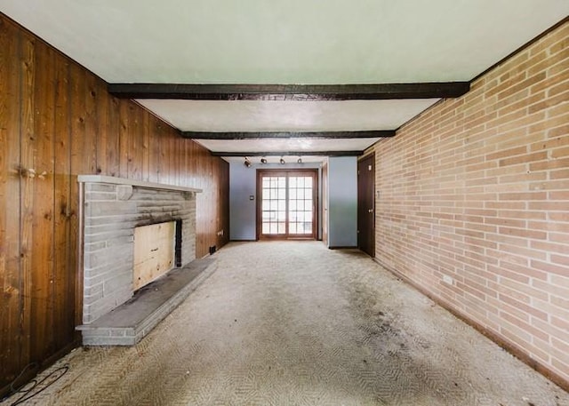 155 Greylock Dr, Penn Hills, PA 15235 - unfurnished living room with wood walls, brick wall, a fireplace with raised hearth, carpet, and beamed ceiling