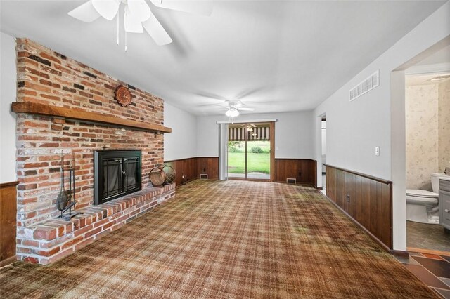 4032 Sardis Rd, Murrysville, PA 15668 - unfurnished living room featuring a wainscoted wall, ceiling fan, a brick fireplace, wood walls, and carpet