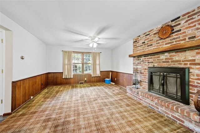 4032 Sardis Rd, Murrysville, PA 15668 - unfurnished living room featuring a wainscoted wall, wood walls, ceiling fan, a brick fireplace, and carpet flooring
